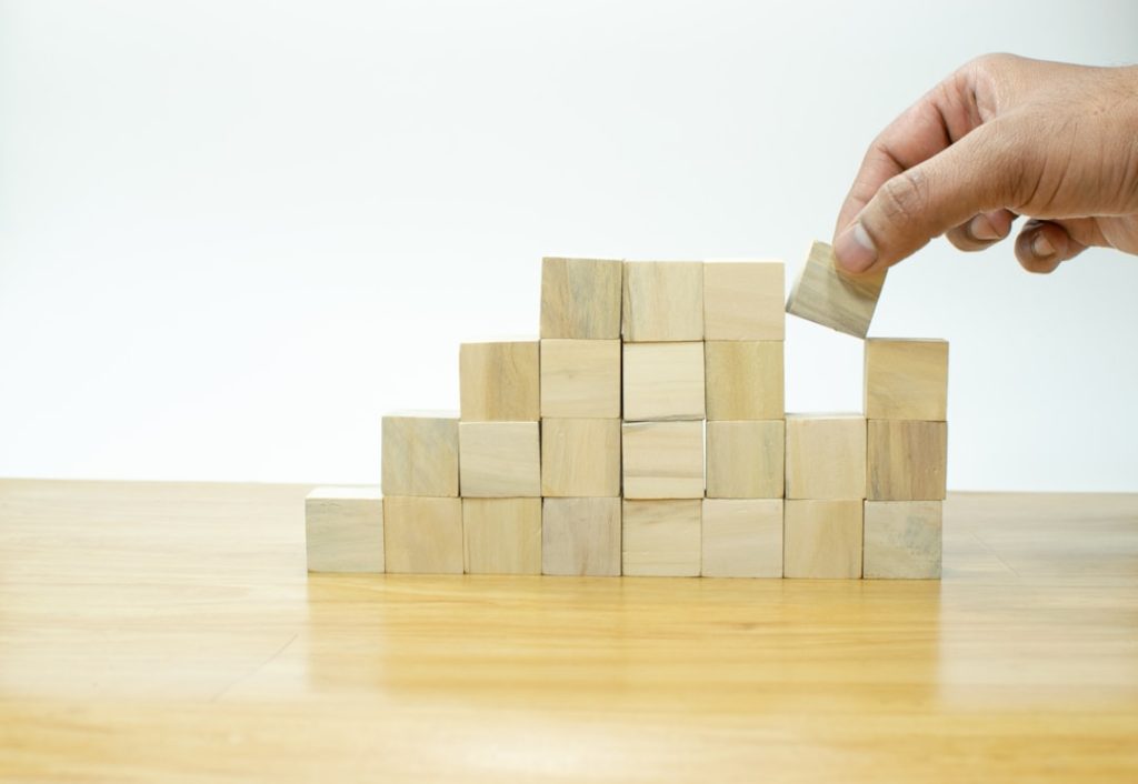Hand arranging wood block stacking as step stair on wooden table, Business concept for growth success process.